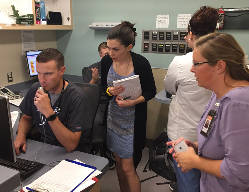 photograph of a crowded nurses' station with a doctor dictating.