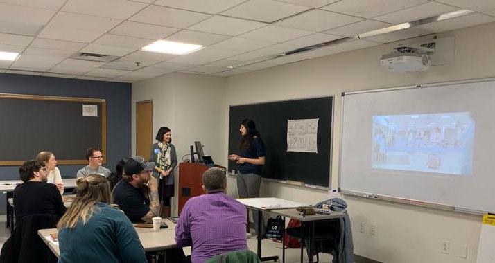 Anna and Theora in front of lectern presenting the theme of Black Mirror episodes as inspiration.